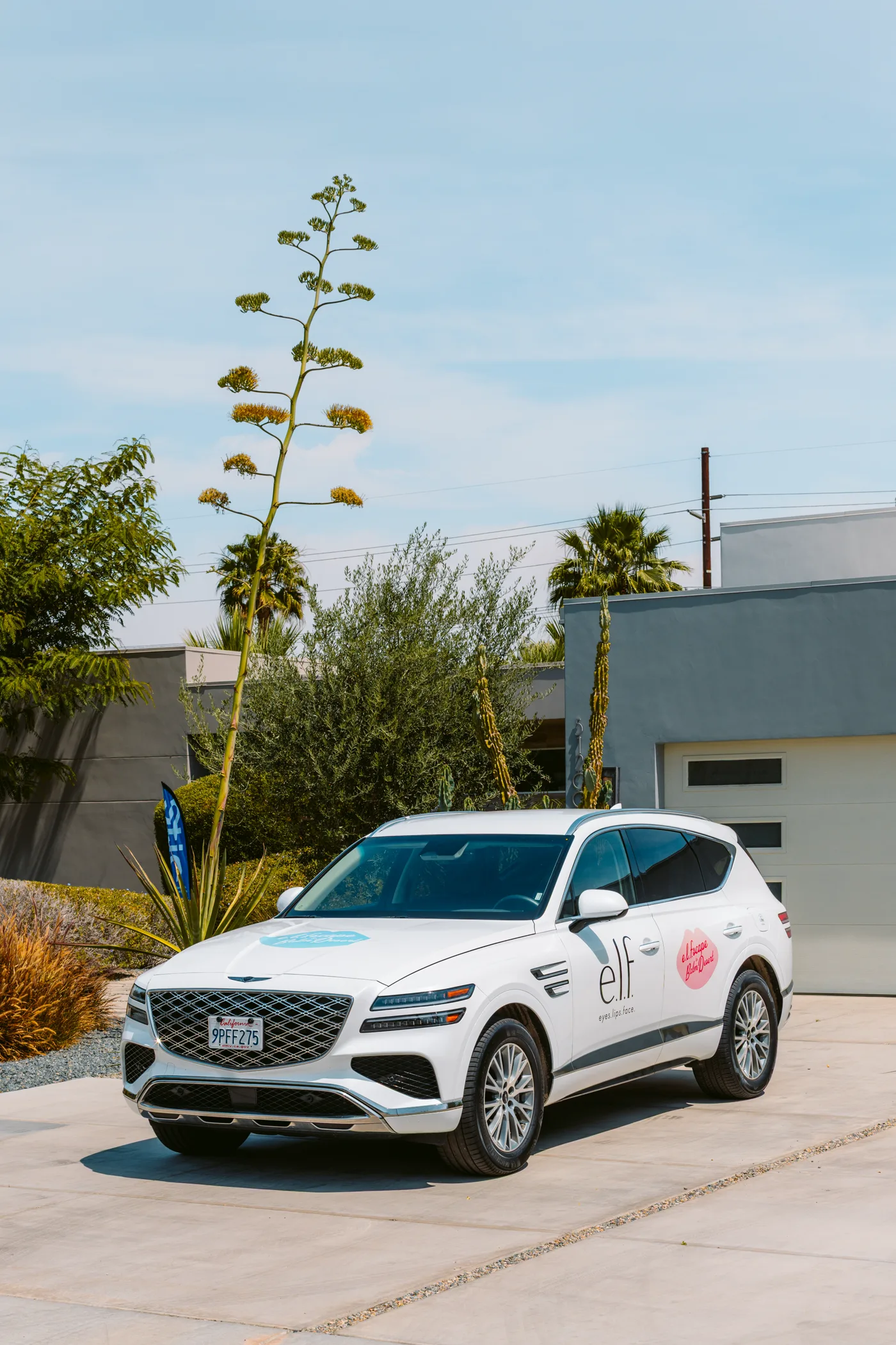 White e.l.f. campaign SUV parked in a desert neighborhood with hood and door stickers visible