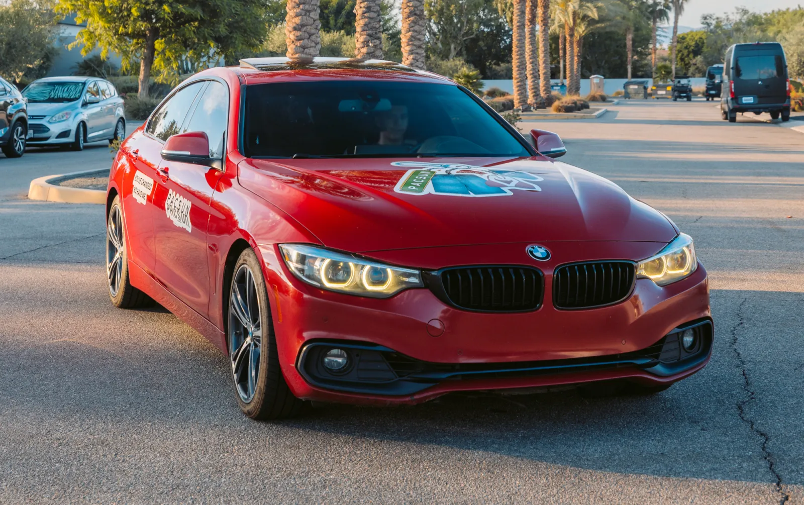 Red BMW coupe with PacSun hood and door graphics in a sunny lot