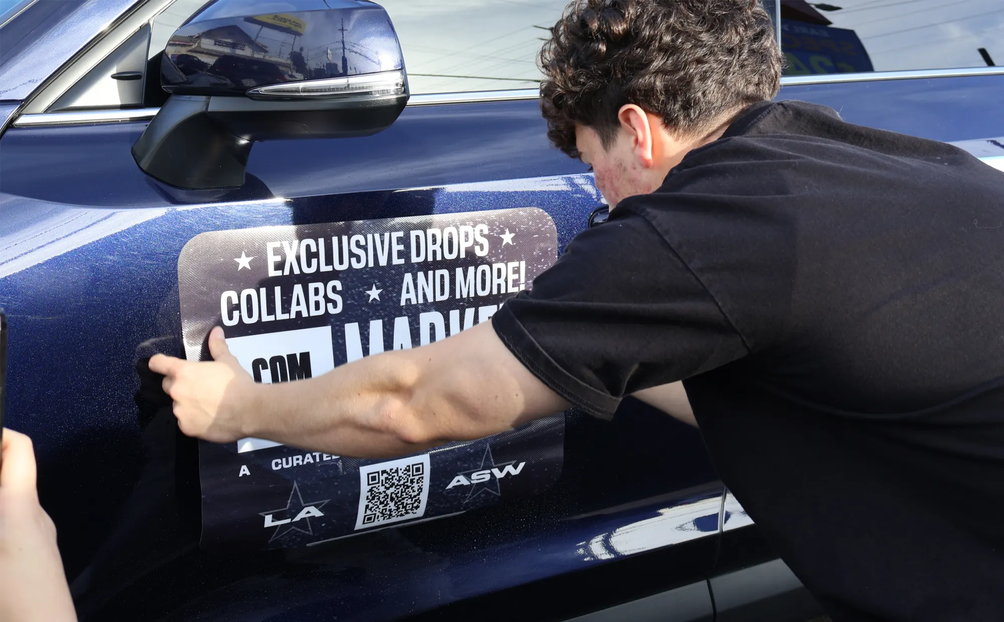 A driver applying a Stic campaign decal to a car door