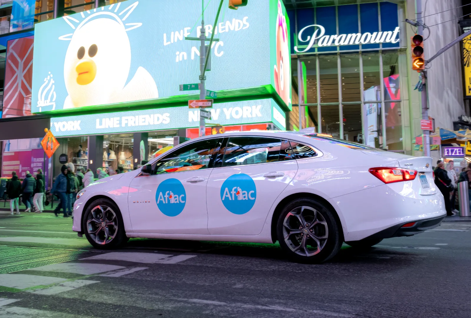Branded campaign vehicle with door placements driving through Times Square